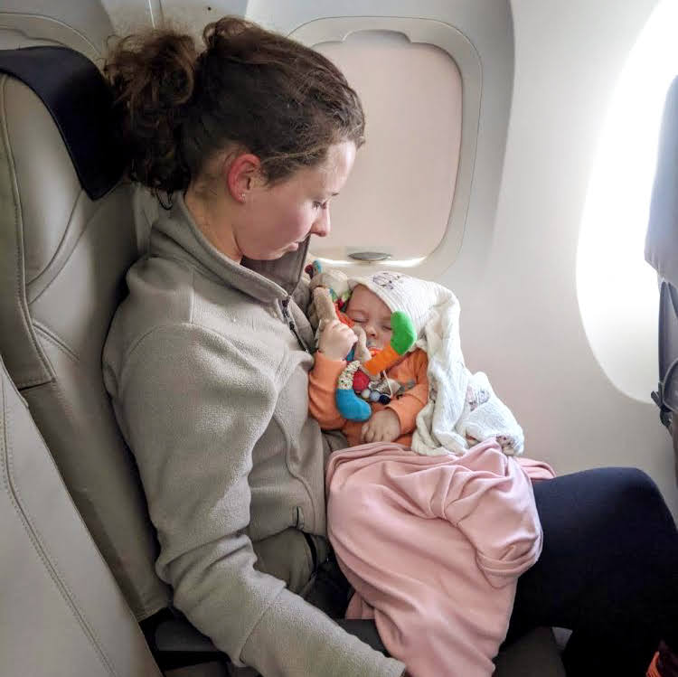 Bébé dort dans les bras de maman en avion